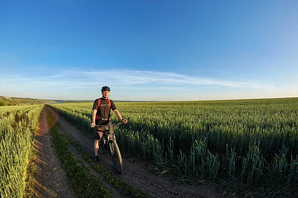 Привабливий велосипедист стоїть з велосипедом і спостерігає за видом на блакитне небо . — стокове фото