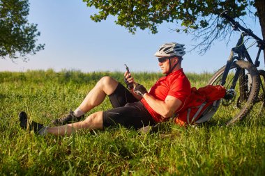 Seyahat bisikletçi yaz öğleden sonra bir dinlenme onun arkasında Onun Bisiklet ile meşe ağacının altında var.