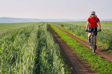 Genç bisikletçi binicilik bisiklet yolun yeşil sahada.