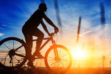 Bir bisikletçi ile gökyüzü arka plan güzel günbatımı üzerinde bisikletle silüeti.