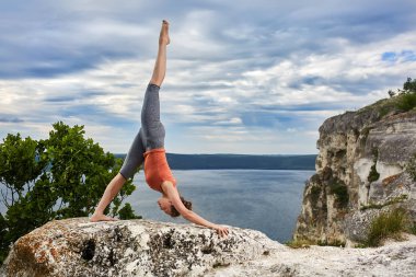 Kayanın üzerinde duran ve nehir üzerinde yoga egzersizleri yapıyor çekici kadın.