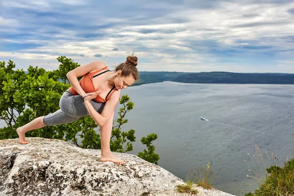 Привлекательная молодая женщина делает позу йоги для баланса на скале . — стоковое фото
