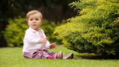 Sevimli küçük bebek kız Şehir Parkı yeşil çayır üzerinde öğrenme.