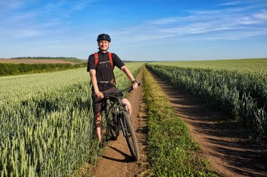 Genç bisikletçi dağ bisikleti güzel manzara arka plan üzerinde ayakta.