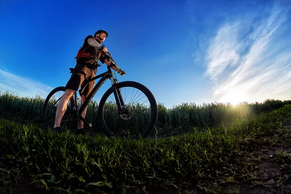 Szeroki kąt rowerzysta, stojąc na szlaku na polu przeciwko piękny krajobraz. — Zdjęcie stockowe