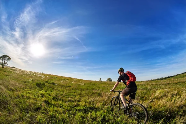 田舎の美しい日の出に対して若いサイクリスト乗馬山自転車. — ストック写真