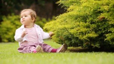 Sevimli küçük bebek kız Şehir Parkı yeşil çayır üzerinde öğrenme.