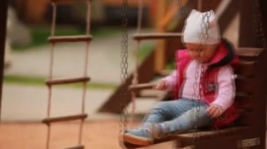 Bebek kız bir salıncak zevk binmek bir oyun Şehir Parkı alanında.