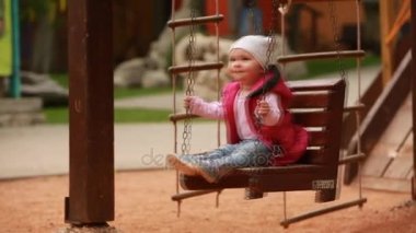 Bebek kız bir salıncak zevk binmek bir oyun Şehir Parkı alanında.