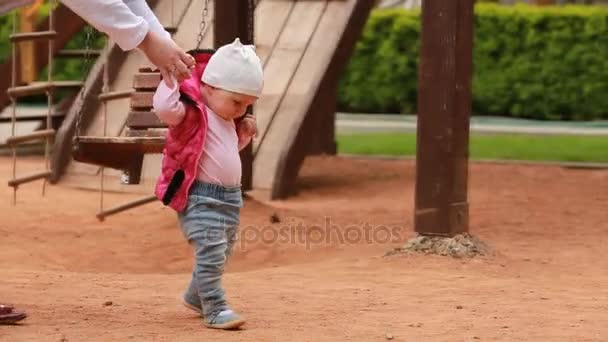 Τα πρώτα βήματα του μικρό χαριτωμένο κοριτσάκι στην παιδική χαρά στο πάρκο πόλης. — Αρχείο Βίντεο