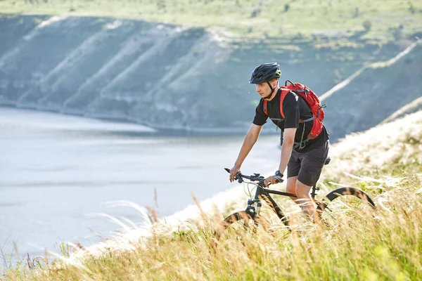 Aantrekkelijke wielrenner rirding mountainbike boven prachtige rivier in het gebied op het platteland. — Stockfoto