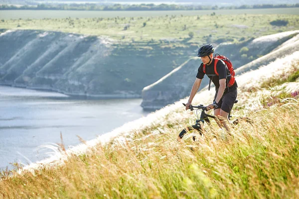 Atractivo ciclista rirding bicicleta de montaña por encima del hermoso río en el campo en el campo . — Foto de Stock