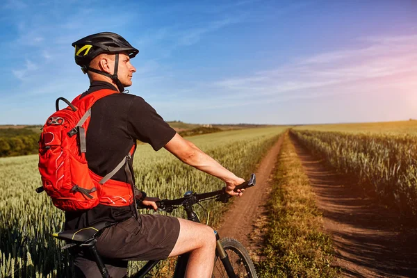 Ελκυστική ένας ποδηλάτης σε mountainbike σε μονοπάτι κοντά σε πράσινο πεδία στην εξοχή το καλοκαίρι. — Φωτογραφία Αρχείου