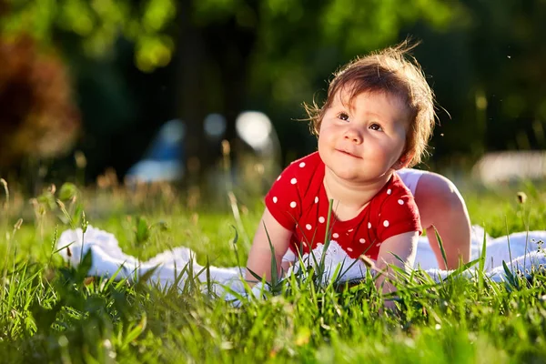 Bonito adorável agradável bebê menina em vermelho primavera vestido sorrindo sentado sob a árvore — Fotografia de Stock