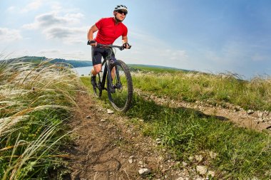 Genç bisikletçi binme dağ Bisiklet güzel gökyüzü karşı yeşil çayır aracılığıyla.