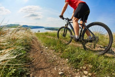 Genç bisikletçi binme dağ Bisiklet güzel gökyüzü karşı yeşil çayır aracılığıyla.