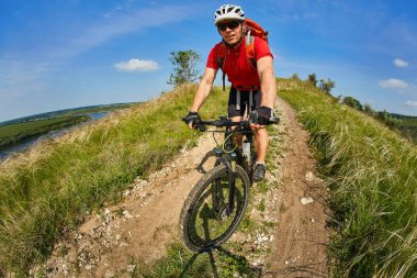 Genç bisikletçi binme dağ Bisiklet güzel gökyüzü karşı yeşil çayır aracılığıyla.