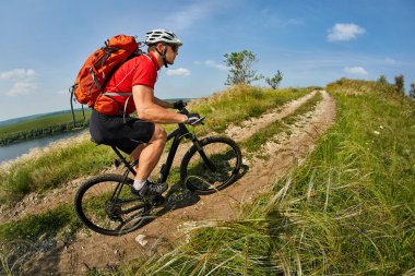 Genç bisikletçi binme dağ Bisiklet güzel gökyüzü karşı yeşil çayır aracılığıyla.