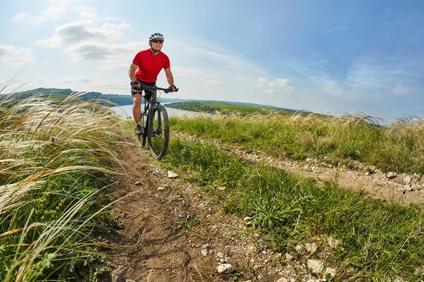 Genç bisikletçi binme dağ Bisiklet güzel gökyüzü karşı yeşil çayır aracılığıyla.