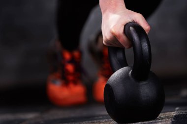 Yakın çekim fotoğraf gönderme yaparken genç atlet kadının el kettlebells salonunda tuğla duvara ups.