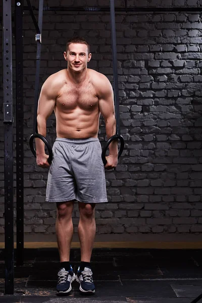 Genç atletik erkek pull ups ile tuğla duvara vasıl jimnastik salonu jimnastik Yüzükler.