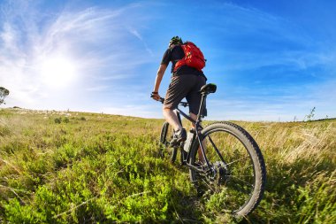 Genç bisikletçi binme dağ bisikletçi güzel gün batımını karşı kırsal kesimde.