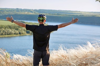 Bisikletçi dağ bisikleti üzerinde sırt çantası ile seyahat waterside üzerinde. Gezgin adventur çayır on riverside üzerinde vardır.