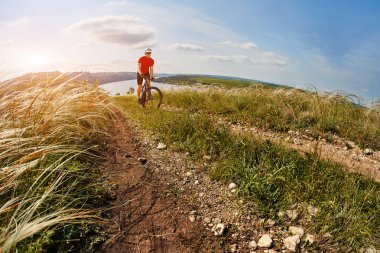 Genç bisikletçi binme dağ Bisiklet güzel gökyüzü karşı yeşil çayır aracılığıyla.