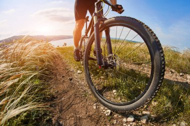 Genç bisikletçi binme dağ Bisiklet güzel gökyüzü karşı yeşil çayır aracılığıyla.