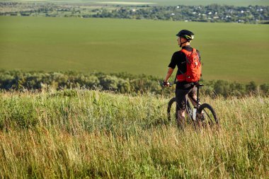 Genç bisikletçi binme dağ bisikletçi güzel gün batımını karşı kırsal kesimde.