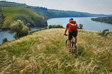 Genç bisikletçi binme dağ Bisiklet güzel gökyüzü karşı yeşil çayır aracılığıyla.