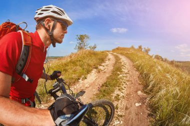 Bir dağ bisikleti ülke yolda sürme turuncu sırt çantası ile kırmızı mayoyu genç yolcusu