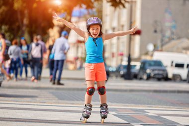 Tekerlekli paten parkta sürme kask içinde komik küçük güzel kız.