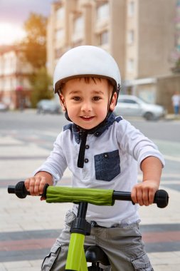 Mutlu çocuk beyaz kask içinde ilk Bisiklete binmek