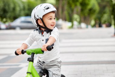 Küçük çocuk çocuk kask içinde Şehir Parkı içinde Bisiklete binmek. Çocuk açık.