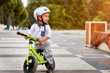 Küçük çocuk çocuk kask içinde Şehir Parkı içinde Bisiklete binmek. Çocuk açık.