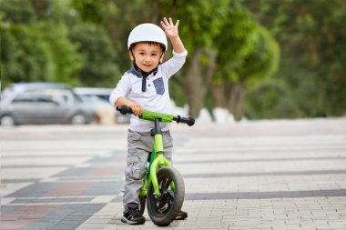 Küçük çocuk çocuk kask içinde Şehir Parkı içinde Bisiklete binmek. Çocuk açık.