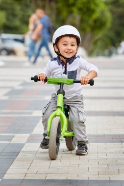 Küçük çocuk çocuk kask içinde Şehir Parkı içinde Bisiklete binmek. Çocuk açık.