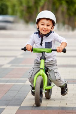 Küçük çocuk çocuk kask içinde Şehir Parkı içinde Bisiklete binmek. Çocuk açık.