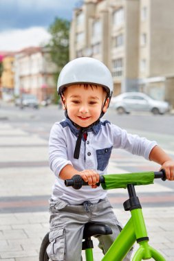 Küçük çocuk çocuk kask içinde Şehir Parkı içinde Bisiklete binmek. Çocuk açık.