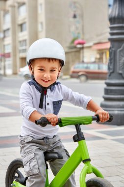 Küçük çocuk çocuk kask içinde Şehir Parkı içinde Bisiklete binmek. Çocuk açık.