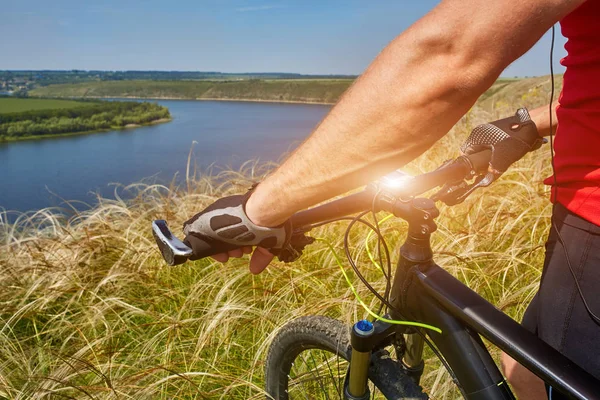 Bisikletçi dağ bisikleti ile güzel gökyüzü karşı yeşil çayır üzerinde seyahat.