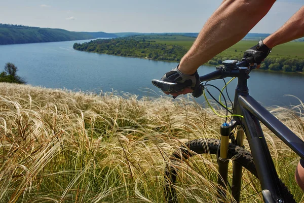 Cestovní cyklista na horském kole přes zelenou louku proti krásné nebe. — Stock fotografie