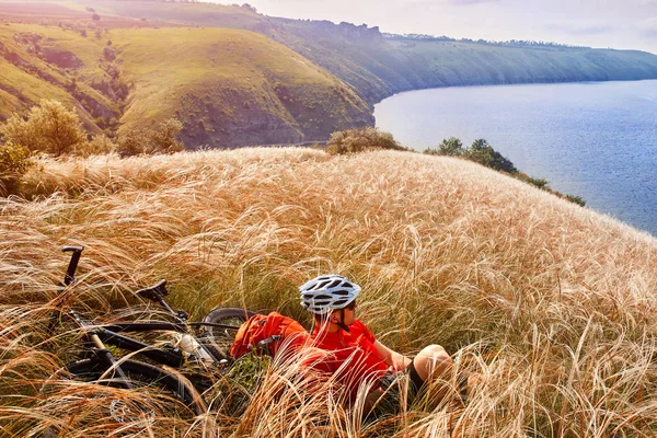 Mountainbike adventur. Radfahrer rastet am Ufer aus. — Stockfoto