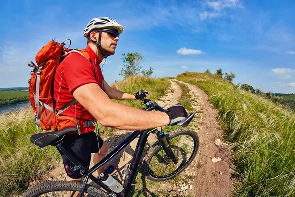 Mladý muž cestovatel jízda na horském kole na západ slunce — Stock fotografie