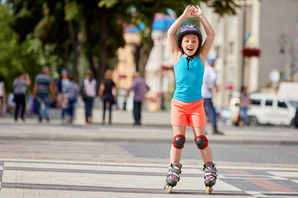 公園で乗馬のヘルメットでローラー スケートで面白い小さなきれいな女の子. — ストック写真