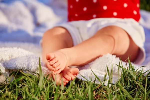 Primer plano de las pequeñas piernas del bebé sobre una hierba verde — Foto de Stock