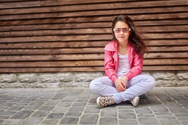 Giyen bir yaz veya sonbahar pembe ceket, beyaz kot pantolon, Güneş gözlükleri şık küçük kız çocuk — Stok fotoğraf