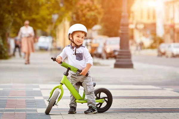 Gelukkige jongen in wit helm zijn eerste fiets — Stockfoto
