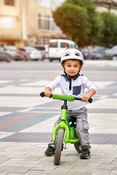 O miúdo de capacete anda de bicicleta no parque da cidade. Criança alegre ao ar livre . — Fotografia de Stock